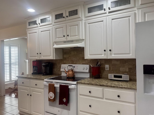 kitchen with white appliances, glass insert cabinets, under cabinet range hood, white cabinetry, and light tile patterned flooring