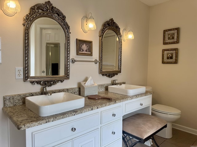 bathroom featuring toilet, double vanity, a sink, and tile patterned floors