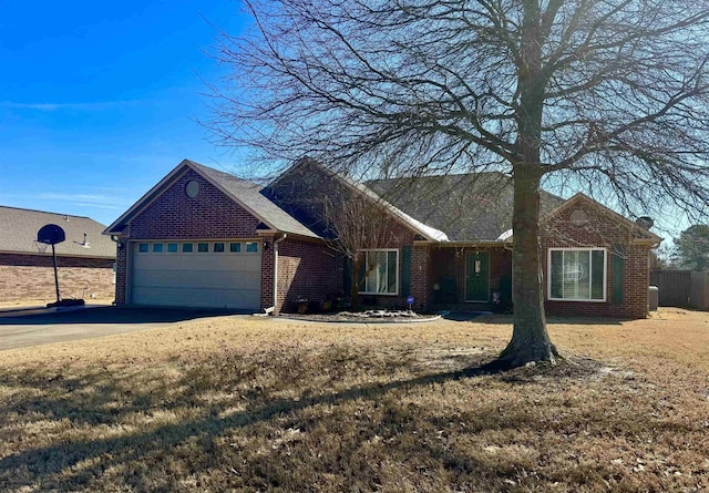 ranch-style house with a garage, concrete driveway, brick siding, and a front yard