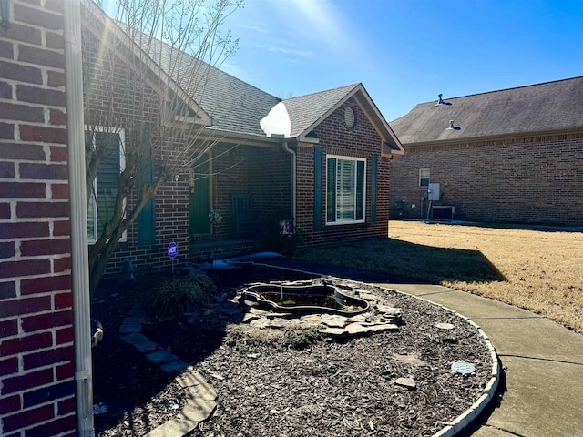 back of property with brick siding and roof with shingles