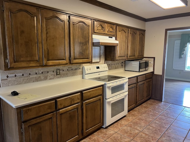 kitchen with range with two ovens, under cabinet range hood, light countertops, ornamental molding, and stainless steel microwave