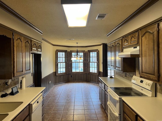 kitchen featuring under cabinet range hood, a wainscoted wall, white appliances, light countertops, and crown molding