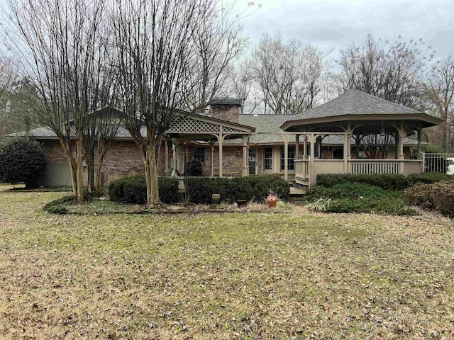 view of front of house with a front yard, a chimney, and a gazebo