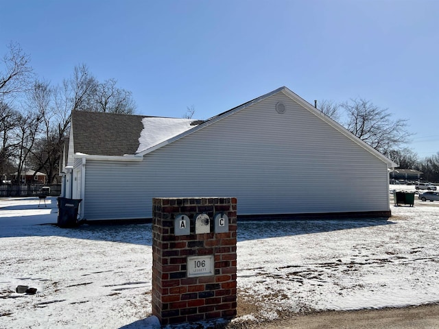 view of snowy exterior featuring roof with shingles