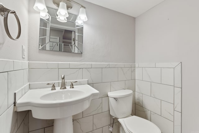 half bath featuring a sink, tile walls, and toilet