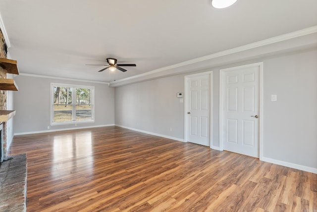 unfurnished living room featuring a ceiling fan, a fireplace, ornamental molding, and wood finished floors