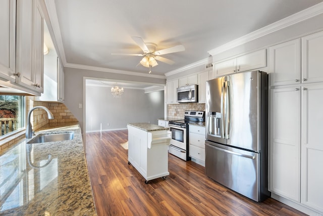 kitchen featuring light stone counters, stainless steel appliances, a sink, a kitchen island, and white cabinets