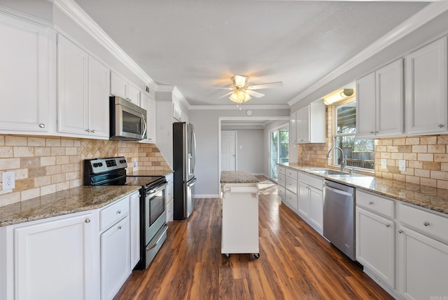 kitchen featuring light stone counters, white cabinetry, stainless steel appliances, and a sink