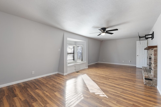 unfurnished living room featuring a barn door, baseboards, a ceiling fan, dark wood-style flooring, and a textured ceiling