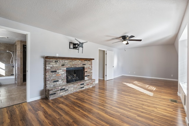 unfurnished living room with visible vents, a ceiling fan, dark wood-type flooring, a textured ceiling, and a fireplace