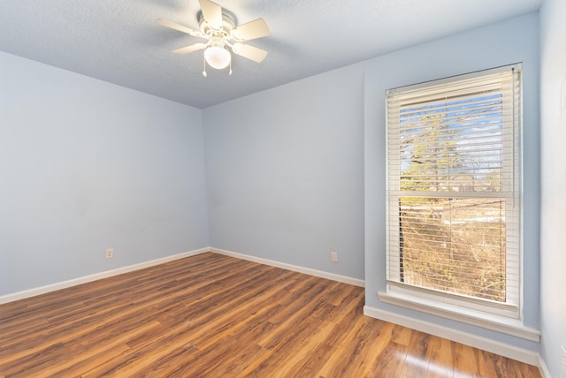 spare room featuring a textured ceiling, wood finished floors, a wealth of natural light, and baseboards