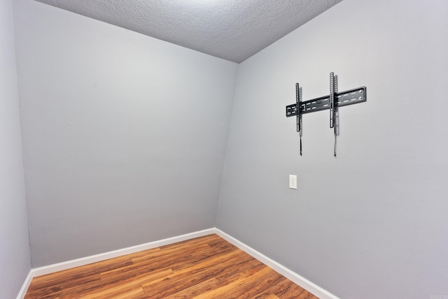 spare room with a textured ceiling, baseboards, and wood finished floors