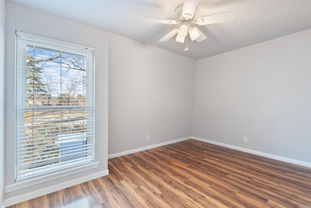 unfurnished room featuring dark wood-style floors, ceiling fan, a textured ceiling, and baseboards