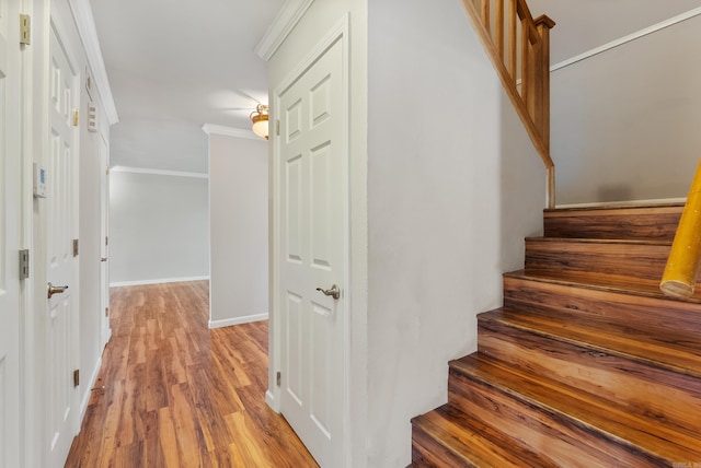 staircase featuring baseboards, wood finished floors, and crown molding