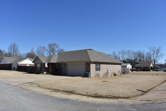 view of home's exterior with an attached garage, a shingled roof, concrete driveway, and brick siding