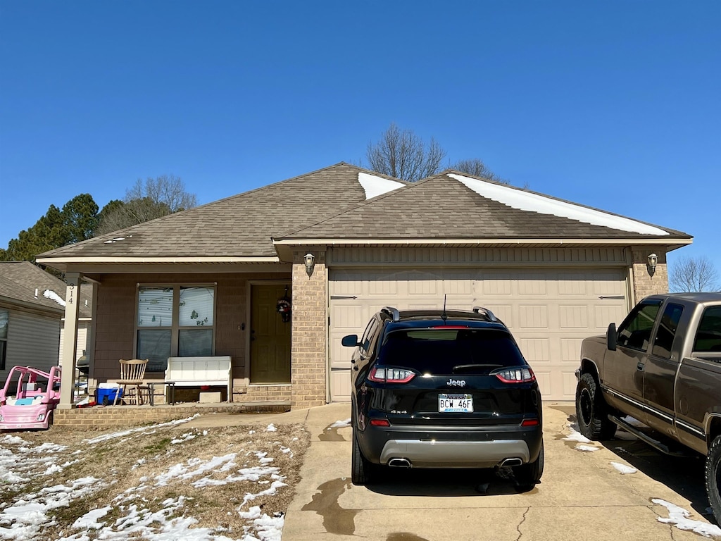 ranch-style home with concrete driveway, a shingled roof, an attached garage, and brick siding