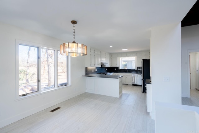 kitchen featuring a peninsula, stainless steel appliances, visible vents, white cabinetry, and dark countertops