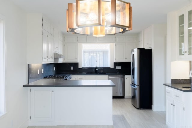 kitchen with appliances with stainless steel finishes, dark countertops, glass insert cabinets, and white cabinets