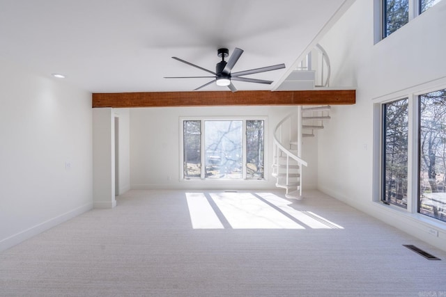 unfurnished living room with a wealth of natural light, visible vents, light carpet, and stairs