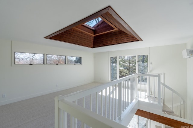 corridor with an upstairs landing, a skylight, carpet, and baseboards