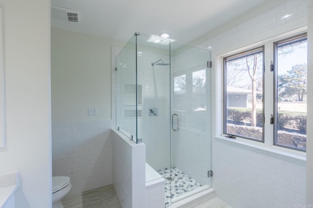 bathroom with toilet, recessed lighting, a wainscoted wall, tile walls, and a stall shower