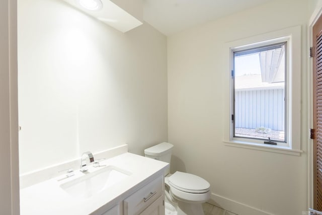 half bath featuring vanity, toilet, and baseboards