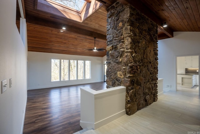 unfurnished living room with lofted ceiling with skylight, wooden ceiling, light wood-style flooring, and baseboards