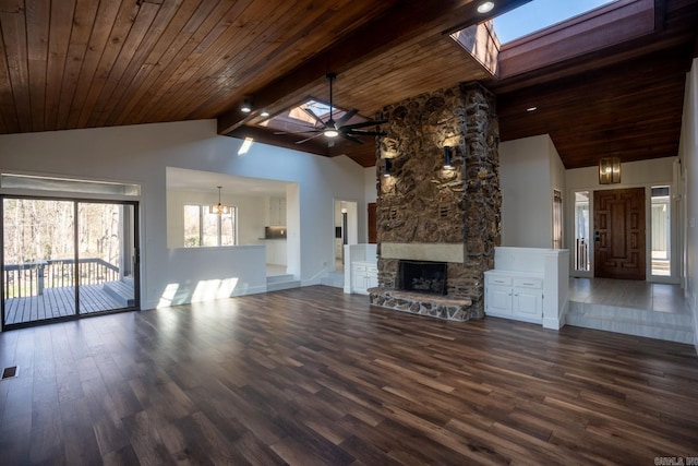 unfurnished living room featuring visible vents, a ceiling fan, dark wood-style floors, wood ceiling, and a stone fireplace