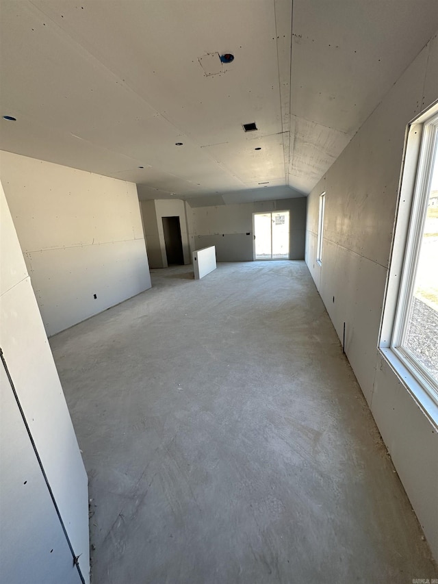 spare room with lofted ceiling, unfinished concrete floors, and visible vents