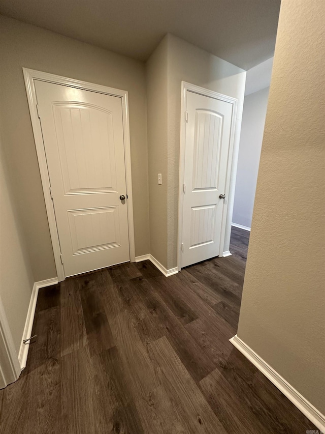 hall with baseboards and dark wood-type flooring