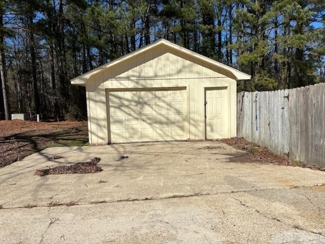 view of outbuilding featuring driveway, fence, and an outbuilding