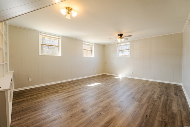 empty room featuring dark wood-style floors, crown molding, ceiling fan, and baseboards