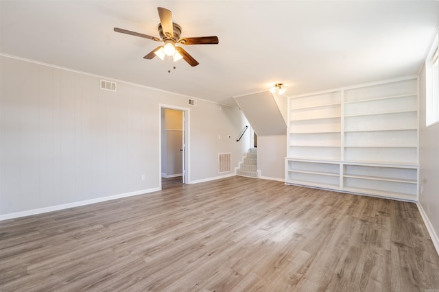 spare room featuring a ceiling fan, light wood-type flooring, visible vents, and stairs