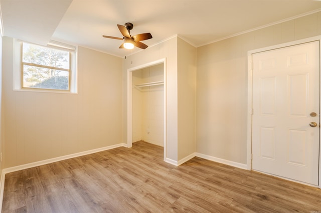 unfurnished bedroom featuring baseboards, a ceiling fan, crown molding, light wood-style floors, and a closet