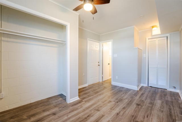 unfurnished bedroom with ceiling fan, baseboards, a closet, light wood-type flooring, and crown molding