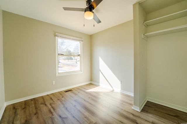 unfurnished bedroom featuring a ceiling fan, visible vents, baseboards, and wood finished floors