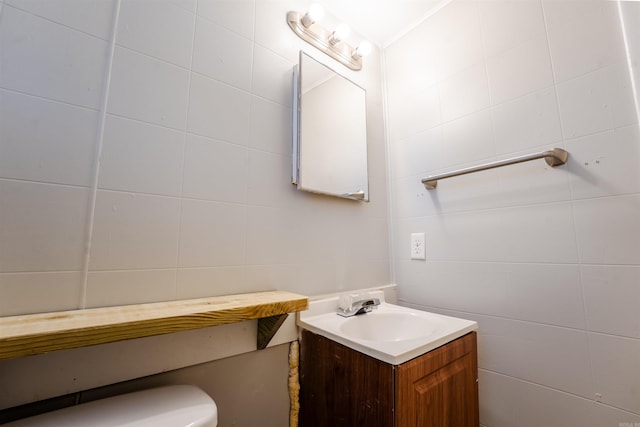 half bathroom with tile walls, vanity, and toilet