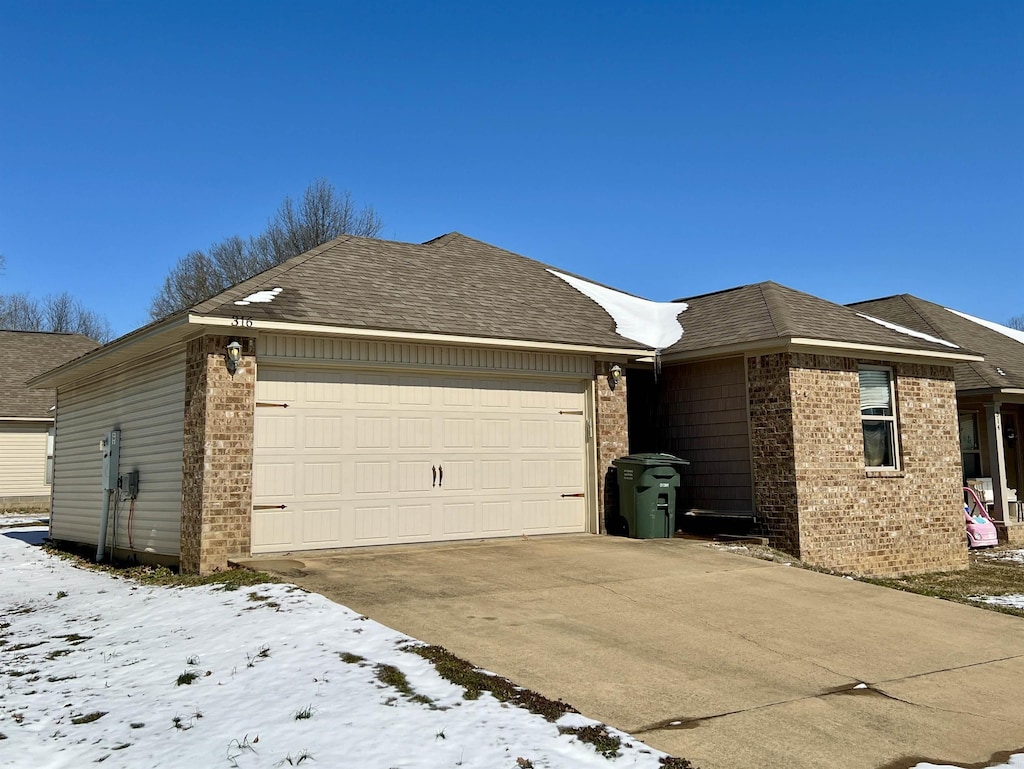 view of front of house featuring concrete driveway, brick siding, an attached garage, and roof with shingles