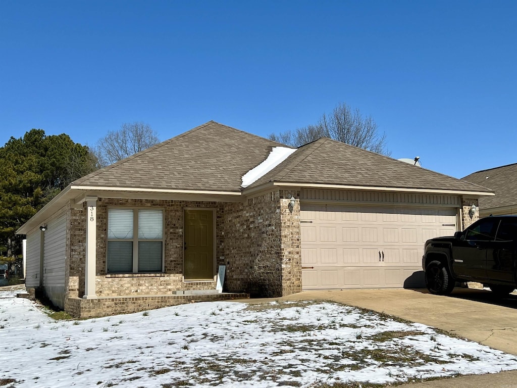 single story home with driveway, brick siding, an attached garage, and roof with shingles