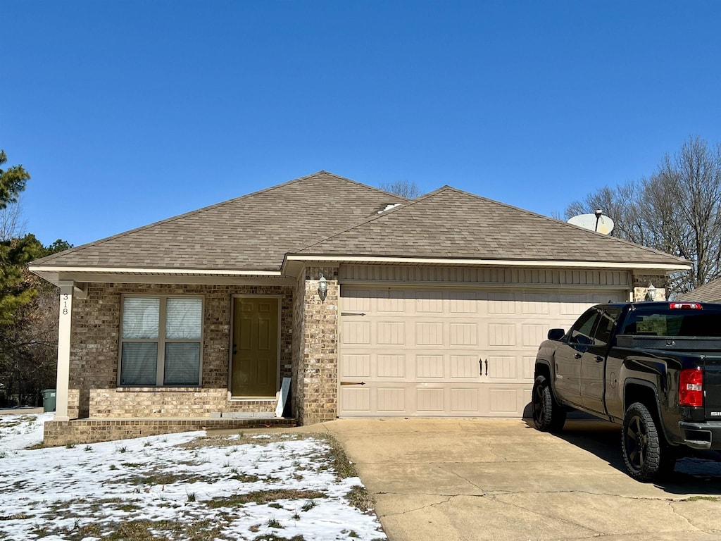 single story home with a shingled roof, concrete driveway, brick siding, and a garage