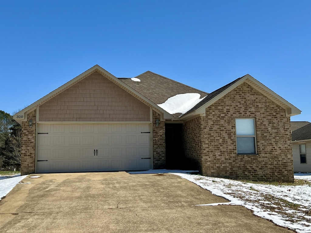 single story home featuring a garage, driveway, and brick siding