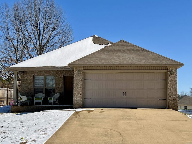 ranch-style home featuring concrete driveway, brick siding, an attached garage, and a shingled roof