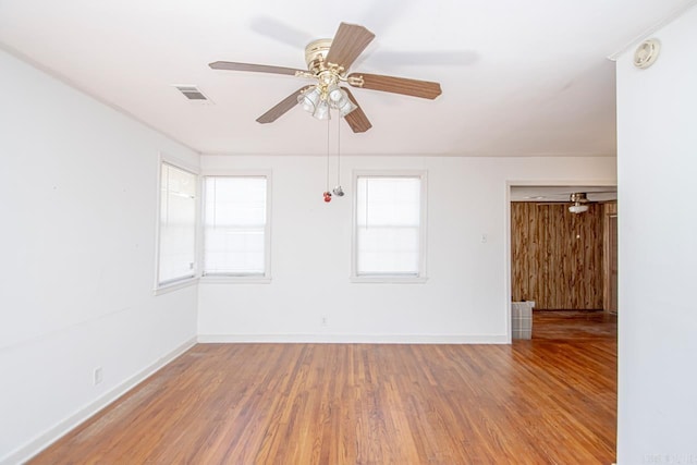 unfurnished room with a wealth of natural light, visible vents, baseboards, and wood finished floors