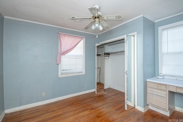 unfurnished bedroom featuring ornamental molding, a closet, wood finished floors, and baseboards