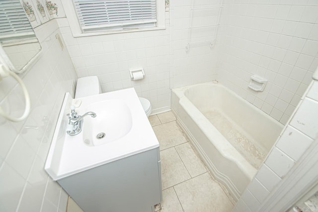 bathroom featuring toilet, vanity, tile walls, and tile patterned floors