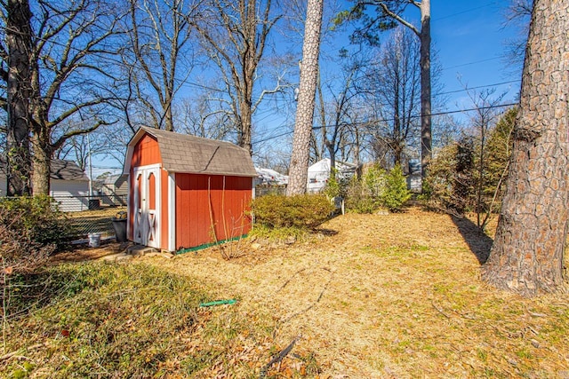 view of yard featuring a storage shed, an outbuilding, and fence