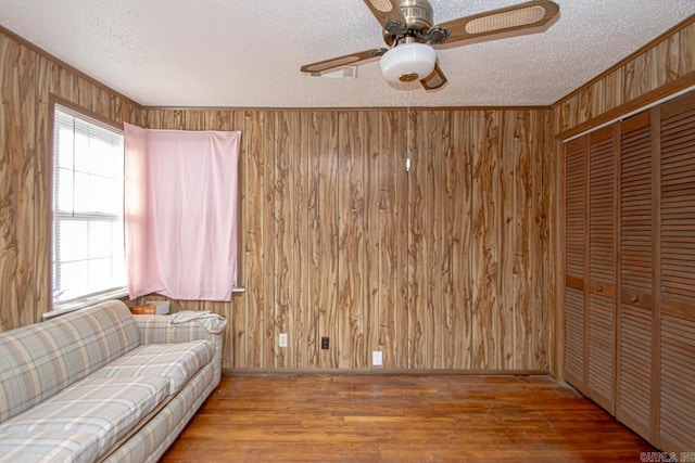 unfurnished living room featuring a textured ceiling, wood walls, and wood finished floors