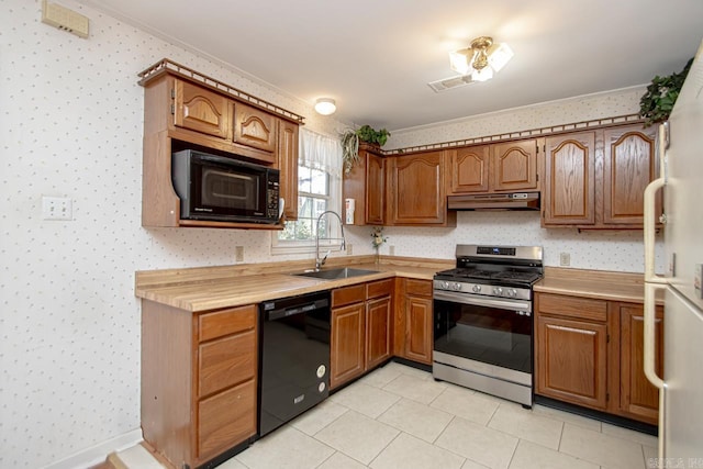 kitchen featuring under cabinet range hood, a sink, brown cabinets, black appliances, and wallpapered walls