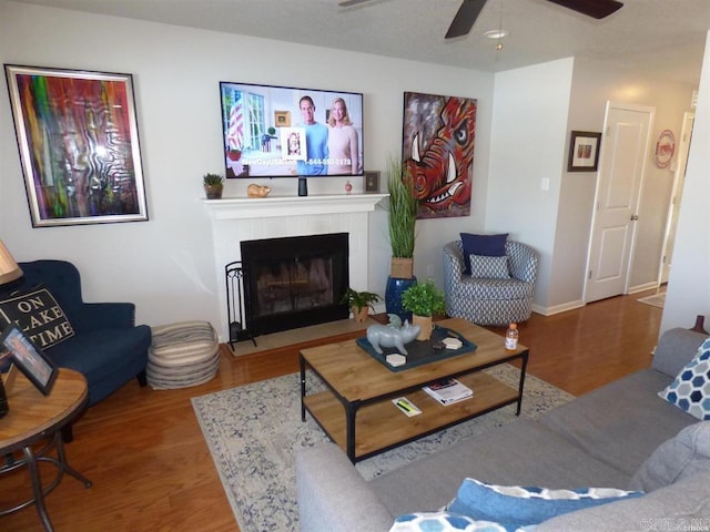 living room with a fireplace, wood finished floors, and a ceiling fan