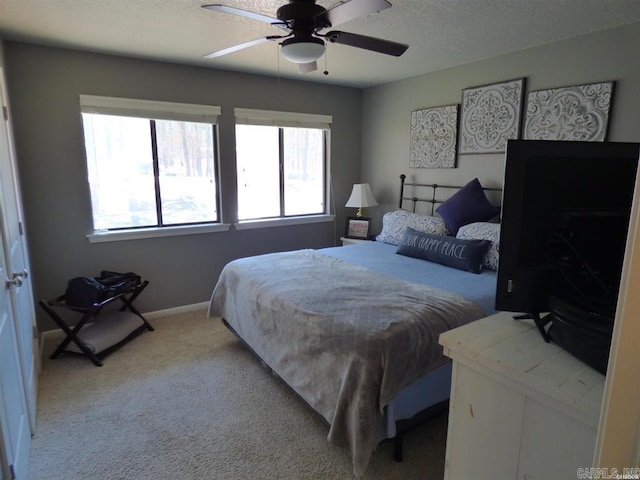 bedroom featuring a textured ceiling, baseboards, a ceiling fan, and light colored carpet